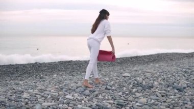 Kadın gündüz egzersiz için çakıl plajda sportif yoga mat yalan olduğunu