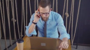 Şirket Müdürü ofiste cep telefonu ile konuşuyor, laptop bakıyor