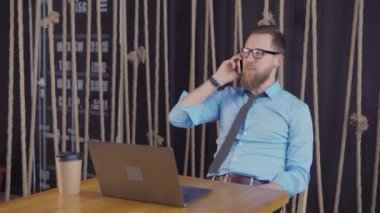 Erkek iş sahibi ofiste oturan ve neşeli cep telefonu tarafından konuşurken