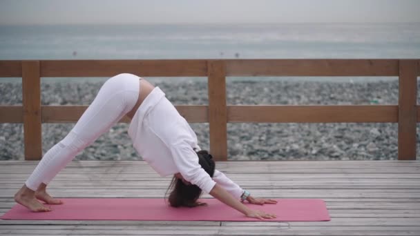 Sportswoman выполняет представления yoga около красивейшего моря — стоковое видео