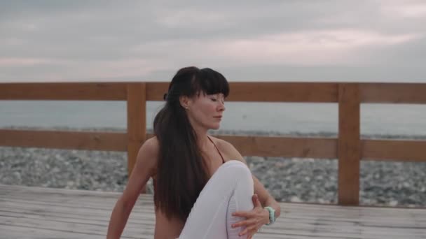 Mulher está fazendo exercícios de ginástica ao ar livre perto da praia do mar na hora da manhã — Vídeo de Stock