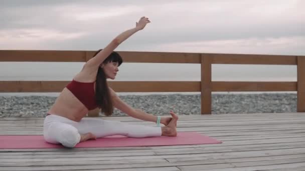 Athlète féminine entraîne son corps par l'exercice physique à l'extérieur près de la mer — Video