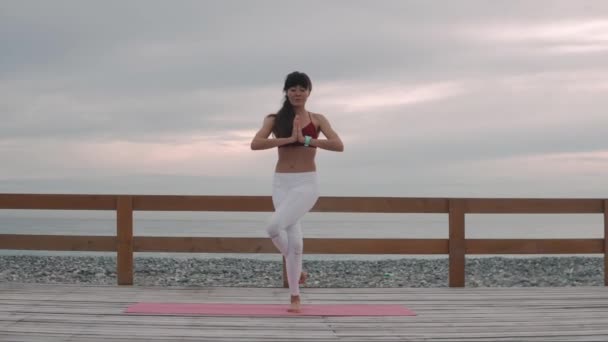 Donna è in piedi in posizione aquila, meditando in serata vicino al mare — Video Stock