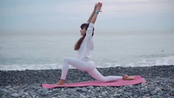 Vrouwelijke atleet is het beoefenen van yoga op Pebble shore of Sea overdag — Stockvideo