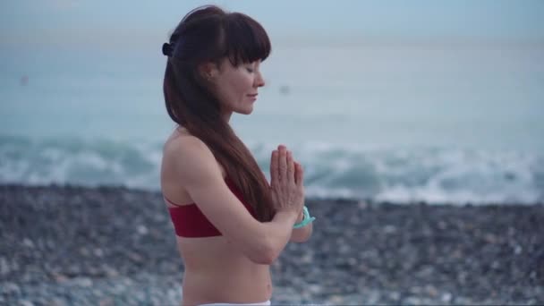 Mujer está meditando tranquilamente en la orilla del mar durante el día, de cerca — Vídeo de stock