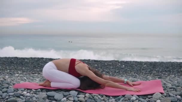 Vrouw is ontspannen op zee strand na de training, liggend gezicht naar beneden — Stockvideo