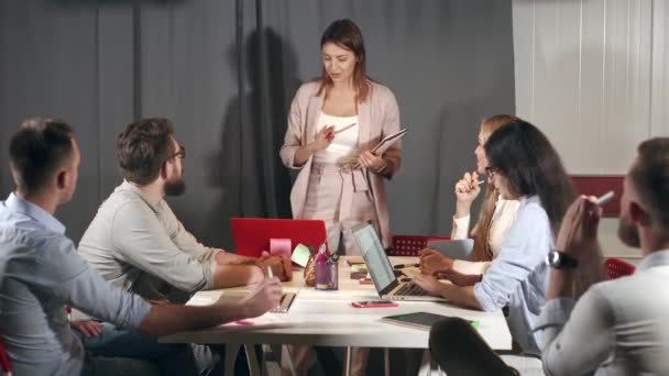 Женщина-специалист представляет свой доклад на встрече, перед своими коллегами — стоковое видео