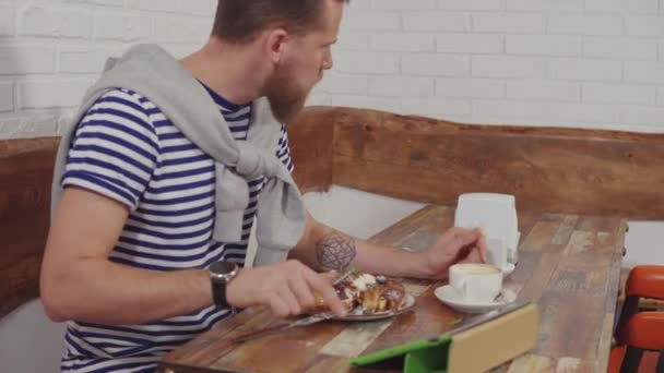 Freelancer homme grignote sur le café et de travailler avec tablette par Internet — Video