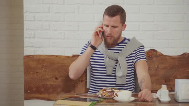 Adulto bonito homem está falando por telefone celular sentado no café de manhã — Vídeo de Stock