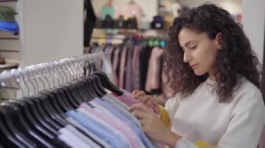 Moda giyim mağazasının kadın alıcı raf bir kazak arıyor