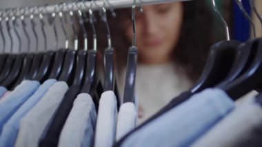 Shopper sportif giyim mağazasında tee shirt ile askıları hareket ediyor, yakın çekim