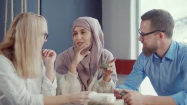Müslüman kadın kafede erkek ve kadın arkadaşlarına hikayeler konuşuyor
