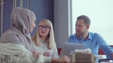 Arkadaşlar odada dinleniyor ve sohbet, sarışın Müslüman kadın soruyor