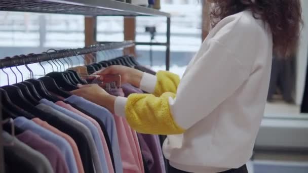 Mujer comprador está tomando dos prendas de rack y entrar en el vestuario — Vídeo de stock