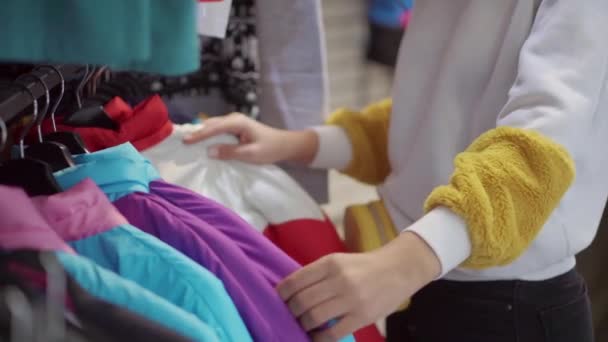 Les mains féminines touchent les cintres avec des vestes chaudes sportives dans le magasin de vêtements — Video