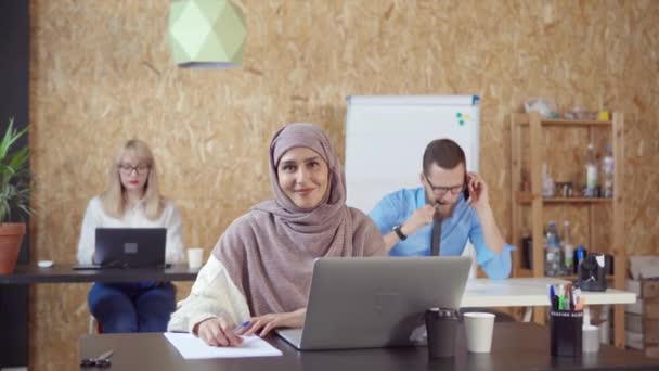 Gladlynt muslimsk kvinna ler brett i kontors rum tittar på kameran — Stockvideo