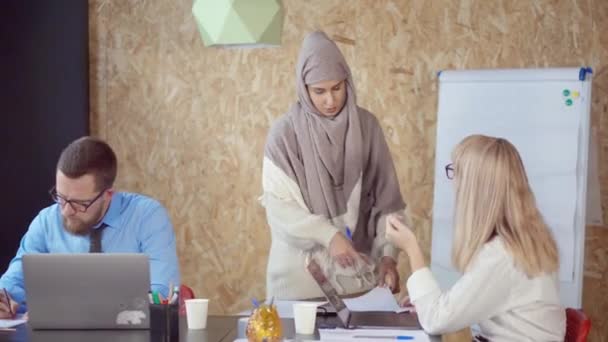 Femeia arabă și caucaziană discută și ia hârtie în biroul modern — Videoclip de stoc