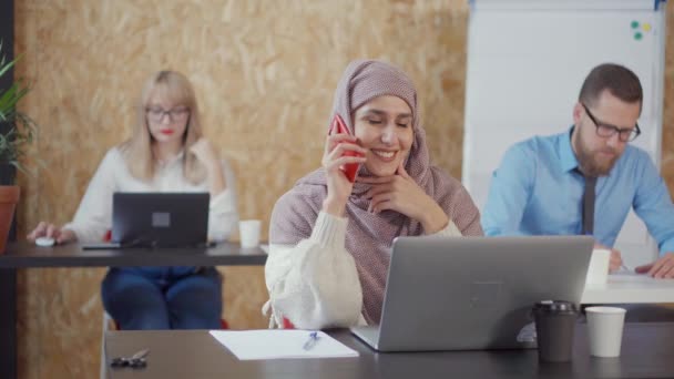 Młoda kobieta z Moslem rozmawia przez telefon komórkowy we współczesnej sali biurowej — Wideo stockowe