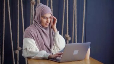 Moslem kadın tek başına istirahat, kafede dizüstü mesajlar yazıyor