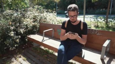 Bir akıllı telefon ile bir bankta turist.