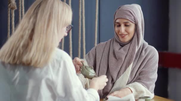 穆斯林和西方传统的妇女在咖啡馆里一起喝茶 — 图库视频影像