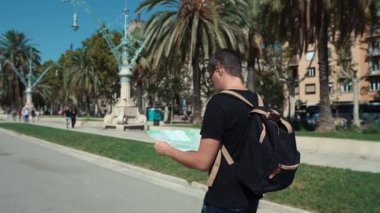 Erkek gezgin, şehir caddesinde tek başına gezinirken kağıt haritasını izliyor