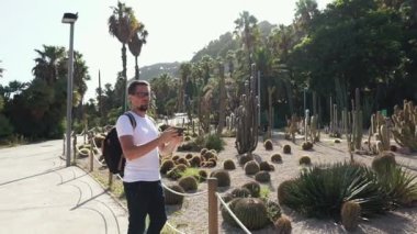 Turist adam cep telefonu tarafından bahçede etli bitkilerin resimlerini alıyor