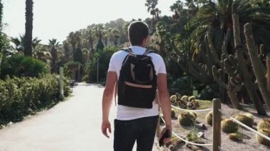 Erkek turist güneşli bir gün Barcelona inanılmaz kaktüs parkta yürüyor