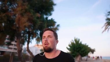 Yorgun genç koşucu gün batımı içinde çalışan, Şehir Parkı alanında akşam eğitim