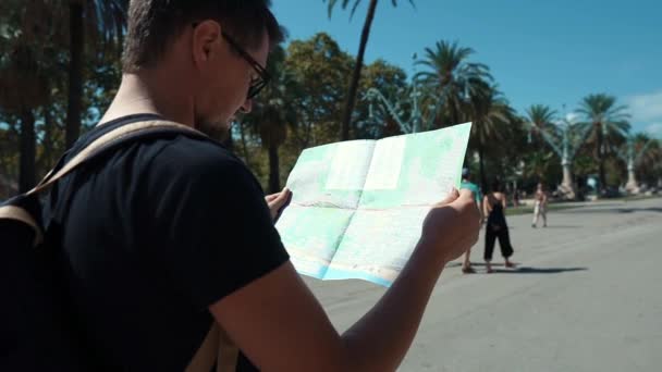 L'homme examine la carte des transports urbains, en regardant autour de la rue — Video