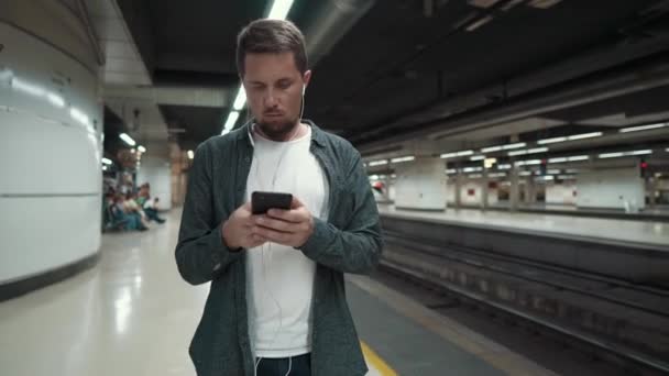 Таунсмен смотрит на экран мобильного телефона на станции метро — стоковое видео