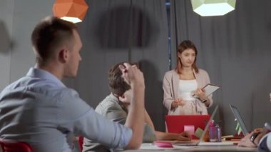 Ofis odasında toplantı, kadın konuşuyor, erkekler birbirleri ile konuşuyor