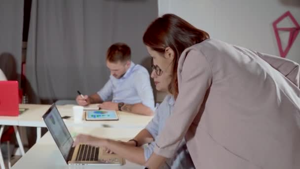 Kvinnan närmar sig kvinnlig arbets tagare på kontoret och tittar på sjökort på laptop — Stockvideo