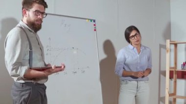 İki uzman iş ortaklarına bir rapor açıklayan, çizelgeleri gösteren