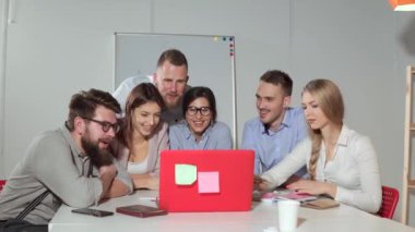 Genç memur işçiler grubu laptop komik video inceleyen, gülümseyen yüzler