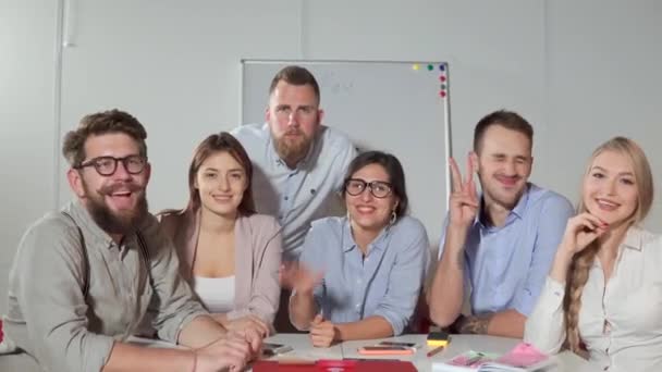 Glückliche junge Leute sitzen im Büro, schauen in die Kamera, wippen mit den Händen — Stockvideo