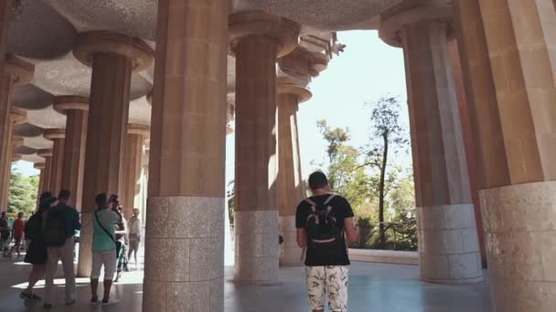 Barcelona, Spanje-September 2018. Enthousiast jonge volwassen toeristische met een kaart lopen onder de kolommen in een Park Guell in Catalonië. Fantastische architectuur van 20 eeuw. Openbare Park gebouwd door Antoni Guell — Stockvideo