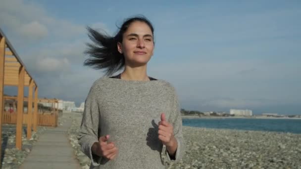 Ευτυχισμένη γυναίκα κάνει το πρωί τρέξιμο στη θάλασσα ακτογραμμή σε ηλιόλουστο καιρό — Αρχείο Βίντεο