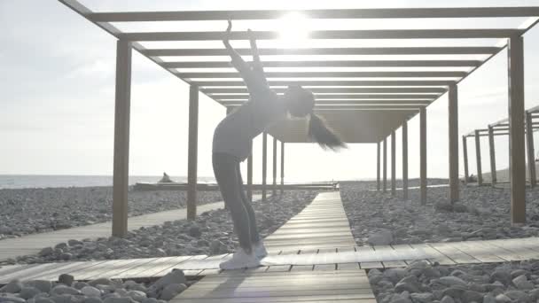 Młoda atletyczna kobieta wykonuje gimnastyczne ćwiczenia mostowe, stojąc z tyłu — Wideo stockowe