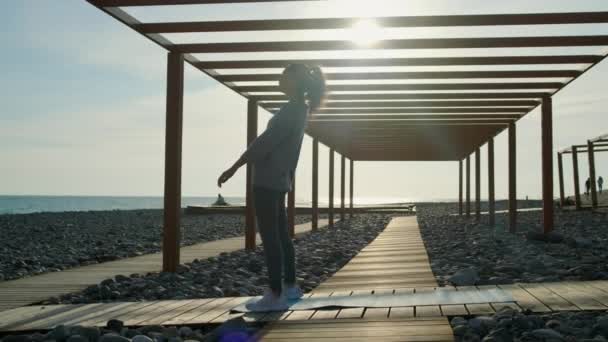 스포츠 여자는 해변에서 차크라사나 운동을 만들고, 다리에 서 — 비디오