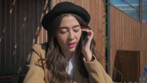 Brunette woman is calling by smartphone and talking joyfully, close-up of face — Stock Video