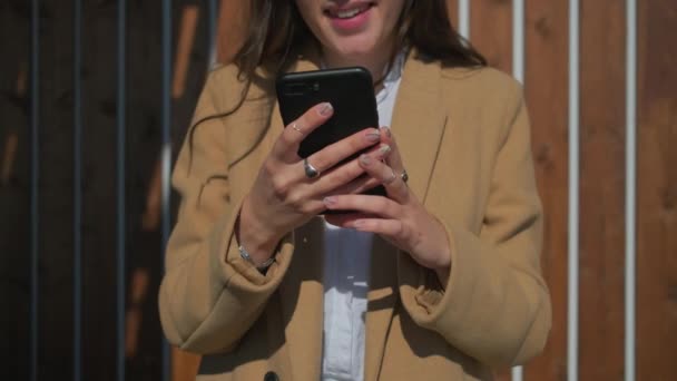 Χέρια νεαρής γυναίκας που κρατά smartphone σε εξωτερικούς χώρους σε ηλιόλουστο καιρό — Αρχείο Βίντεο