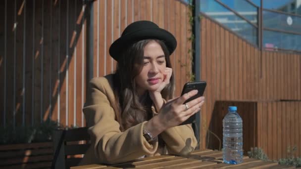 Einsame junge Frau plaudert an sonnigen Frühlingstagen im Freien mit dem Smartphone — Stockvideo