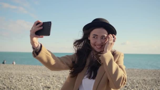Affascinante ragazza sta girando video di se stessa da fotocamera mobile in spiaggia soleggiata — Video Stock
