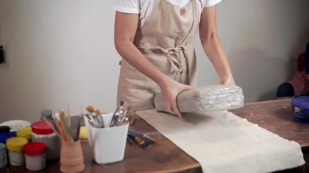 Vrouw beeldhouwer is snijden pack met grijze klei in workshop — Stockvideo