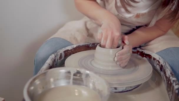 Ceramista femenina está dando forma a la taza de arcilla en la rueda de alfareros en el taller — Vídeo de stock