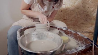 Genç seramikçi kadın çömlekçi dükkanında tek başına çalışıyor.