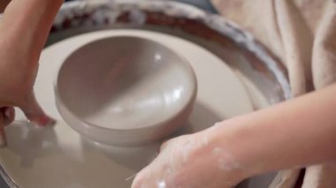 Potter çömlekçi tekerleğinden seramik kase kesiyor, yakın çekim görünüm