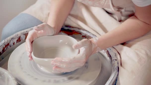 Жіночий гончар розтягує глину на гончарне колесо в студії, роблячи чашу — стокове відео