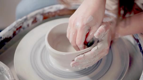 La mujer está mojando y suavizando la arcilla en la rueda de alfarería en cerámica, primer plano — Vídeo de stock